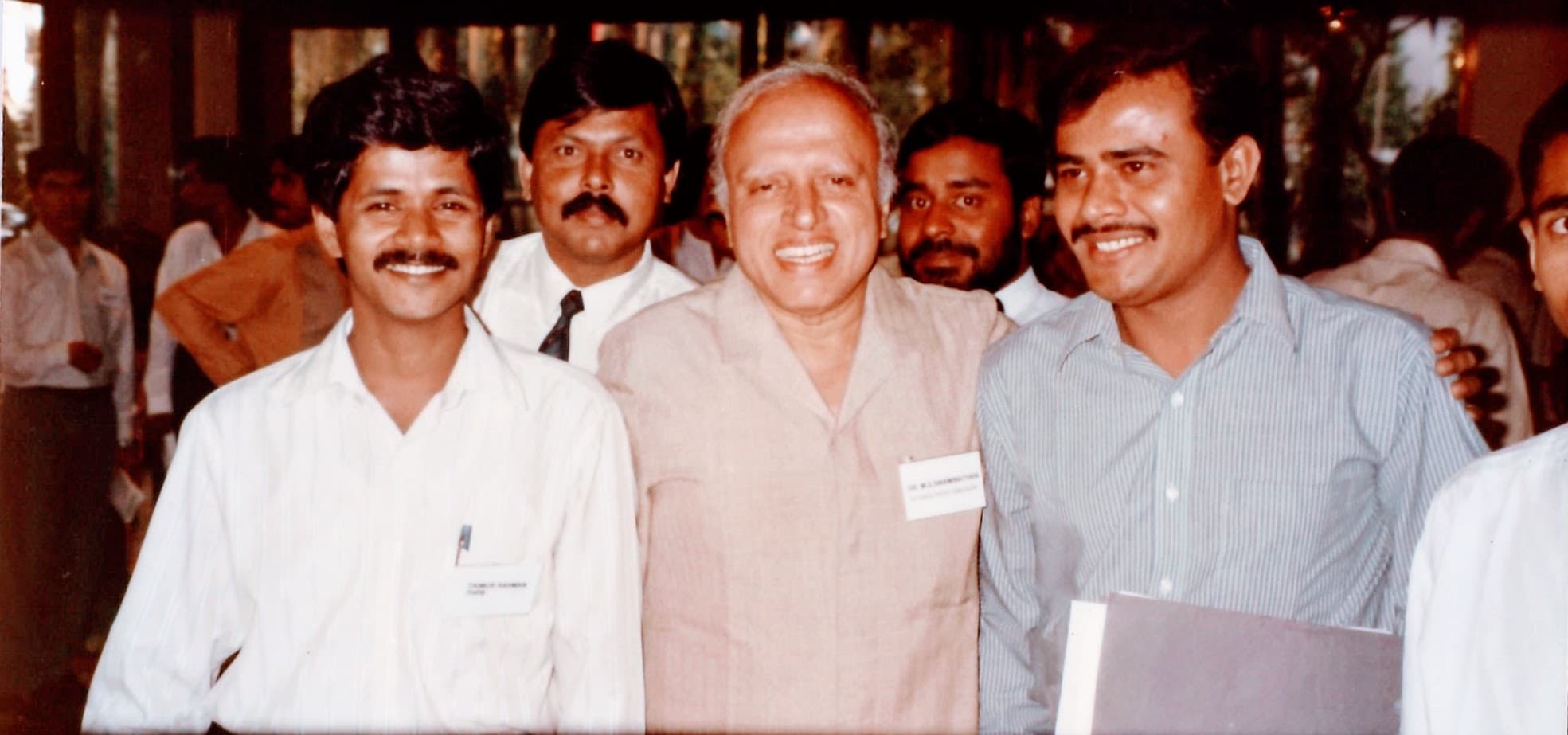 Dr. Swaminathan stands three men from Bangladesh at a meeting.