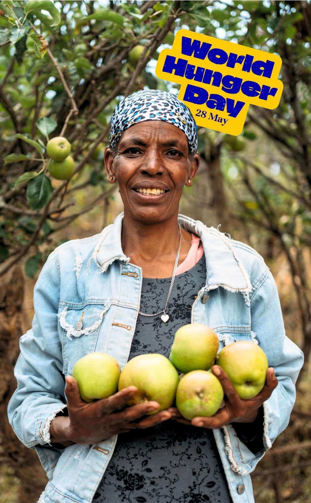 Woman in Ethiopia holding fresh fruit in an orchard with World Hunger Day graphic in the background.