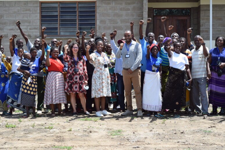 Group of people standing with their hands raised in front of a building in Malawi